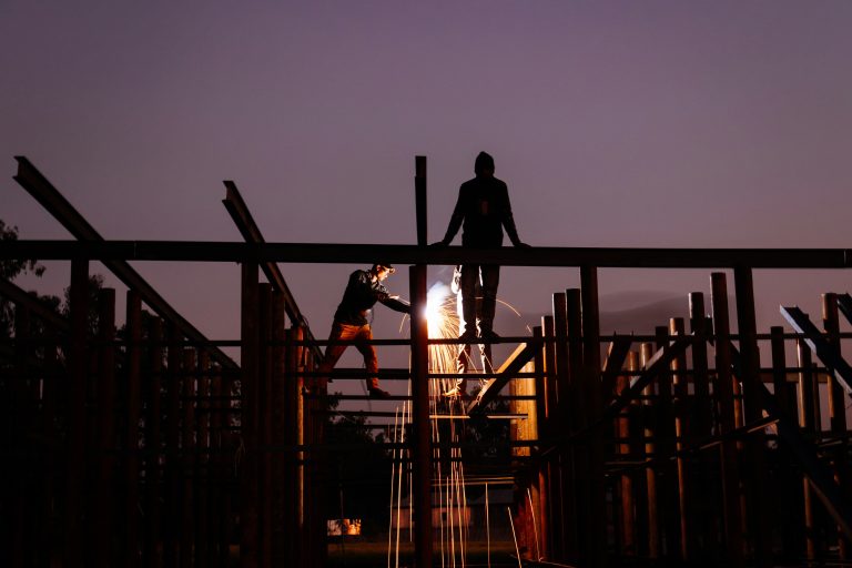 Two construction workers on beams carrying out hot works