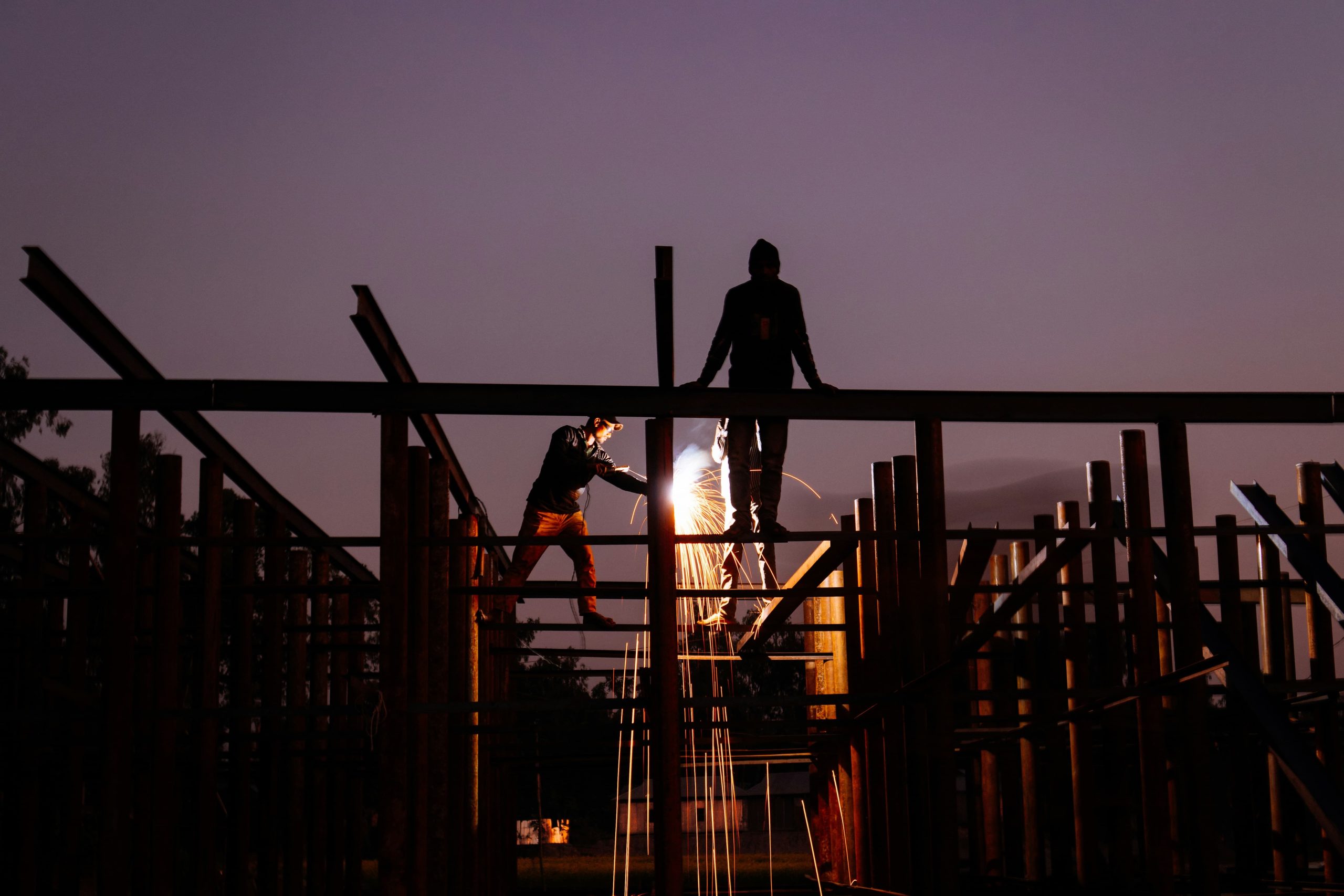 Two construction workers on beams carrying out hot works