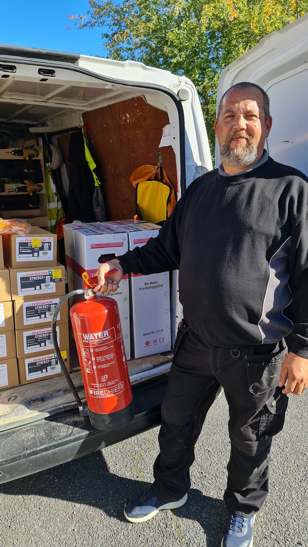 Man holding fire extinguisher standing in from of servicing van