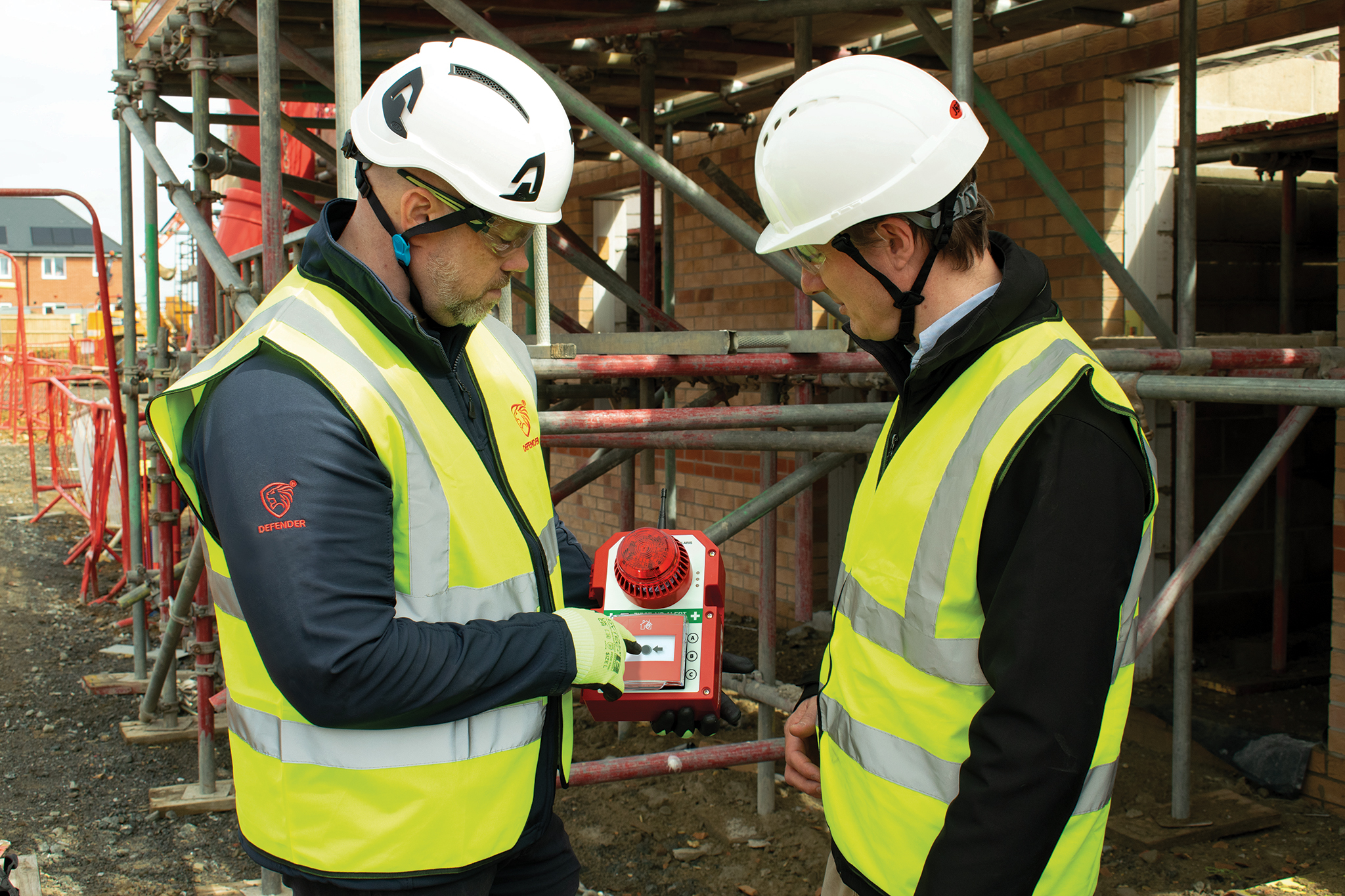 Workers wearing PPE pointing to fire alarm system